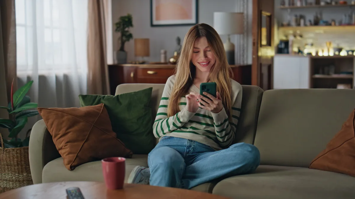 A resident filing a record from her phone at home on the sofa